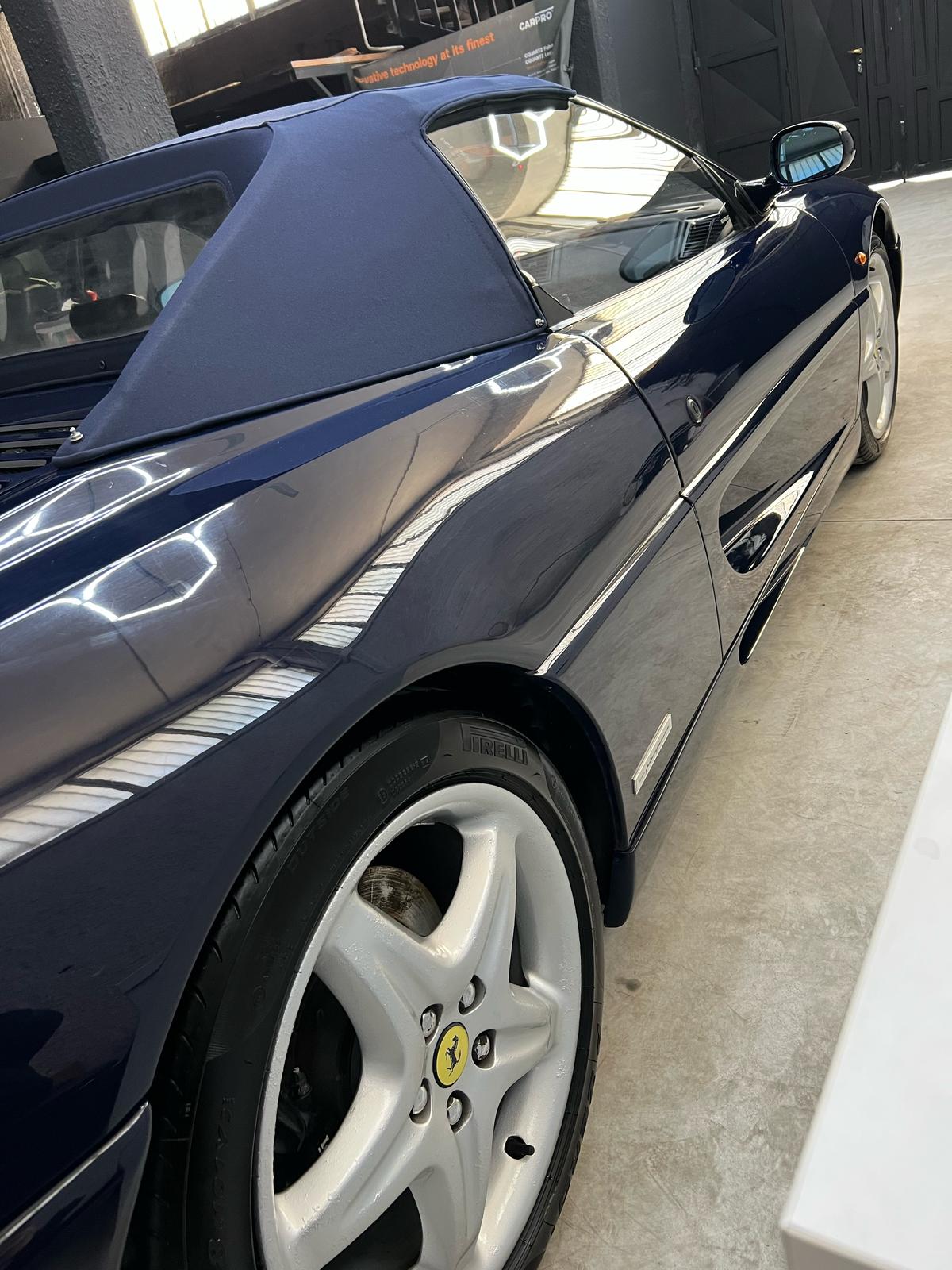 Riflessi sulla fiancata di una Ferrari F355 blu in atelier